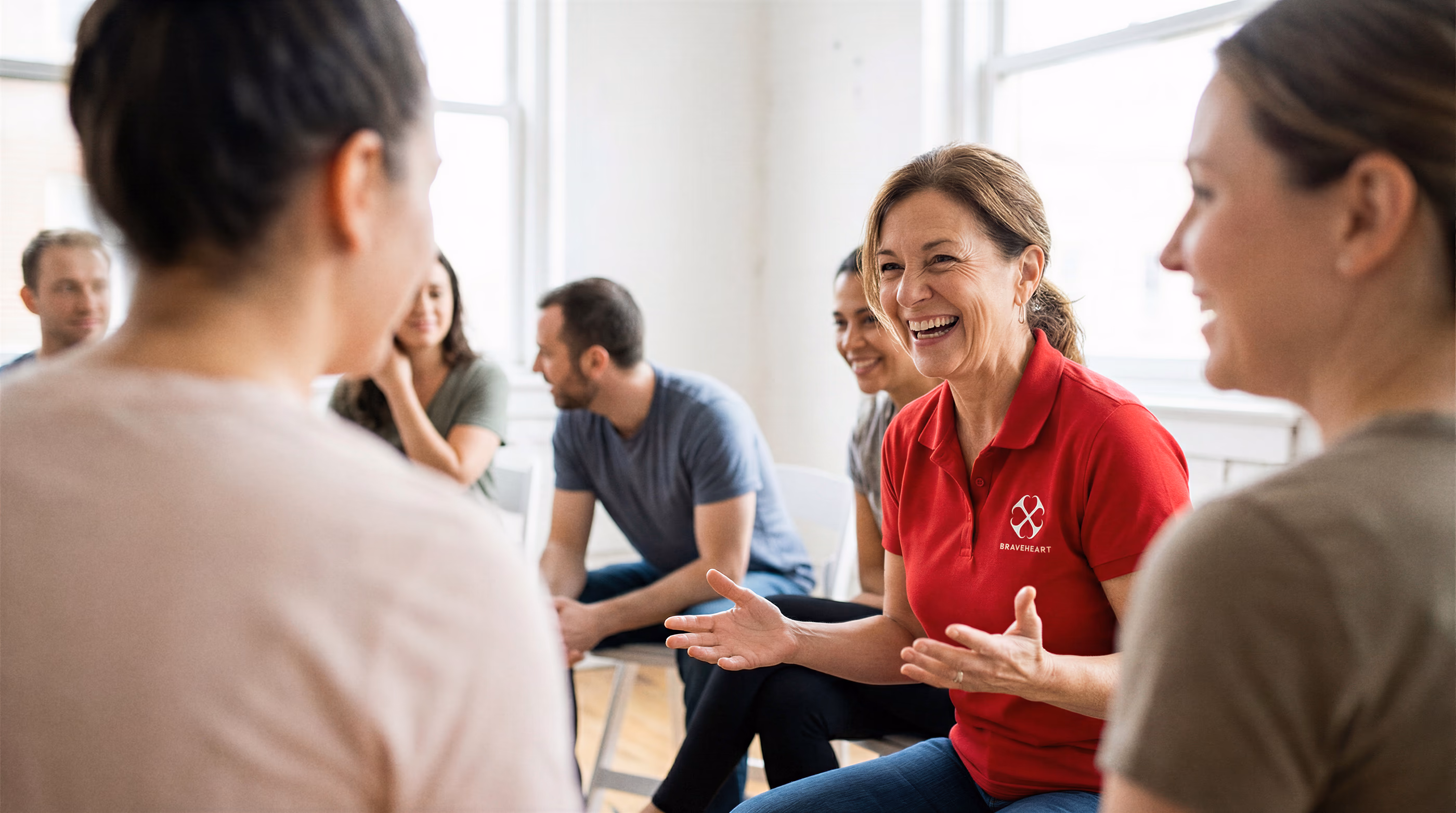 A BraveHeart instructor in a red polo leading a relaxed group discussion