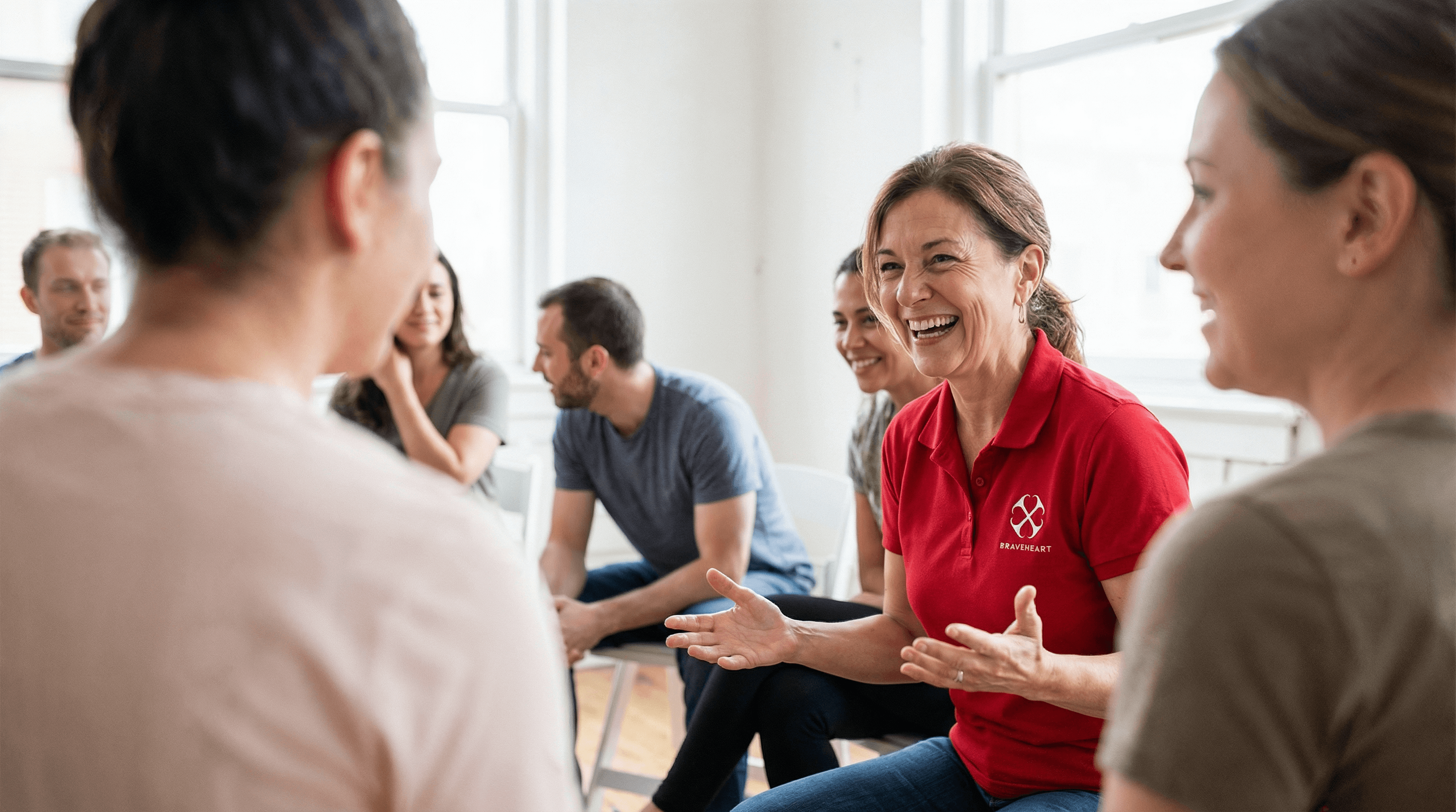 A BraveHeart instructor in a red shirt leading a group first aid training conversation